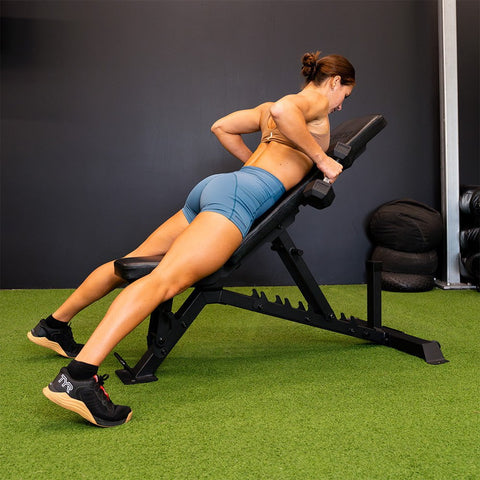 A lady doing dumbbell rows on the Force USA® Commercial FID Bench